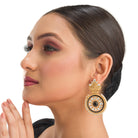 "Gold-tone earrings with black pearl add elegant warmth and striking contrast to any outfit."
