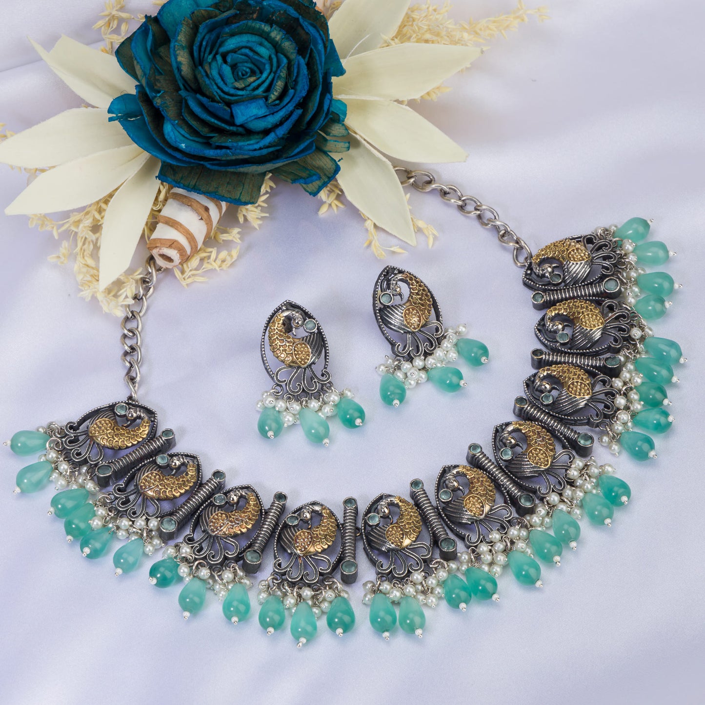 AN OXIDIZED NECKLACE WITH GREEN KUNDAN AND WHITE PEARLS EXUDES VINTAGE ELEGANCE.