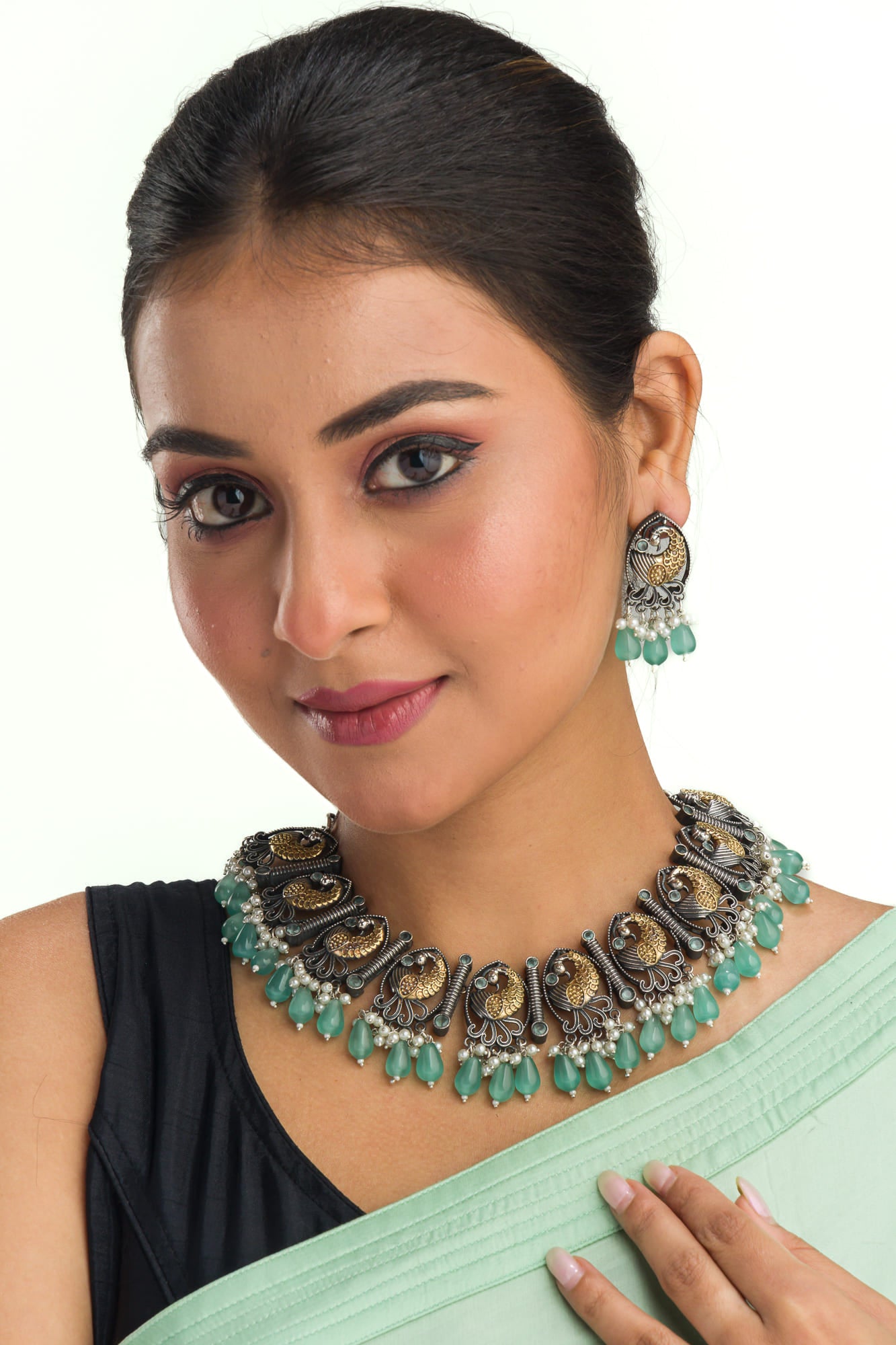 AN OXIDIZED NECKLACE WITH GREEN KUNDAN AND WHITE PEARLS EXUDES VINTAGE ELEGANCE.