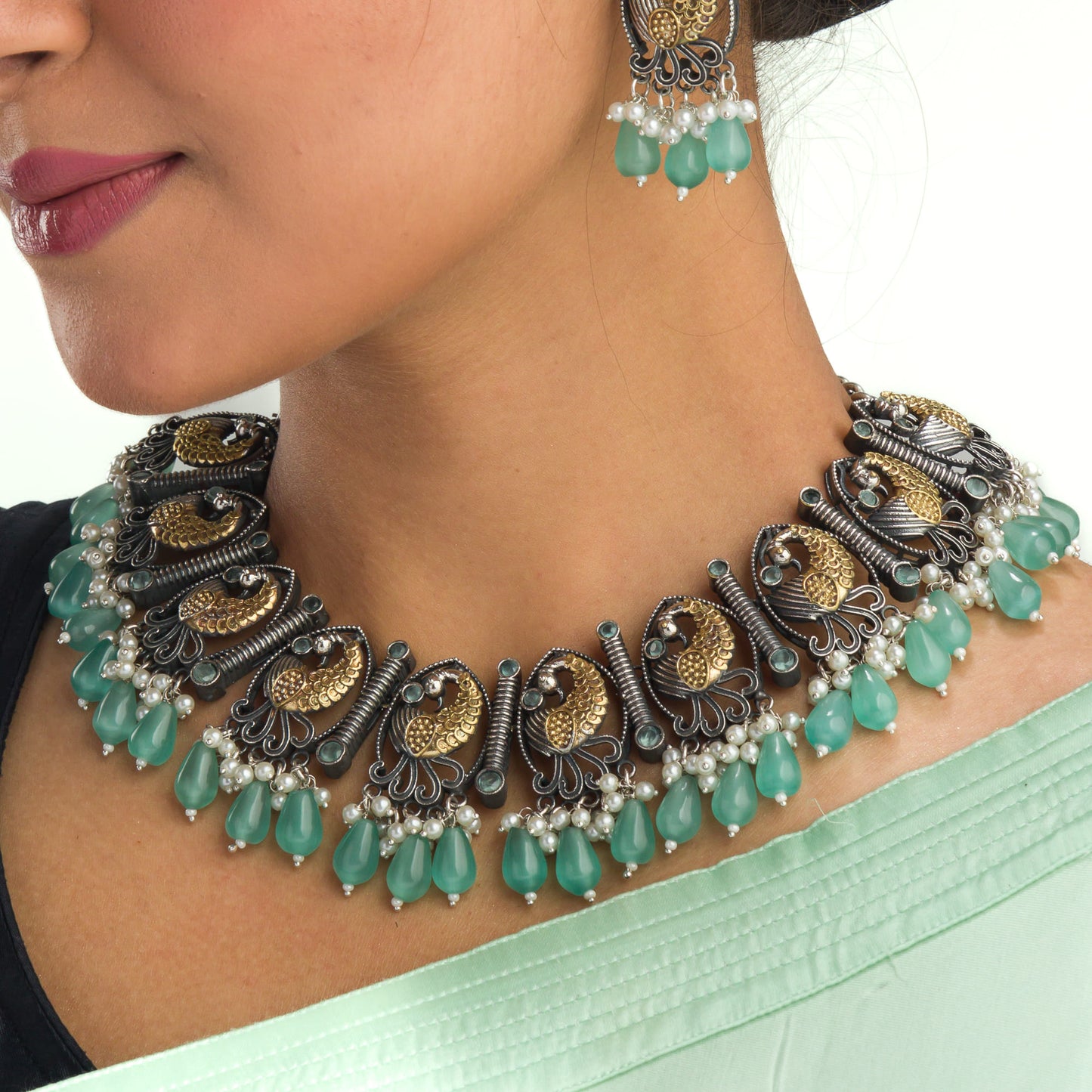 AN OXIDIZED NECKLACE WITH GREEN KUNDAN AND WHITE PEARLS EXUDES VINTAGE ELEGANCE.