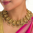 Vibrant gold-tone necklace with red, green stones, and white pearls for a stunning party look.
