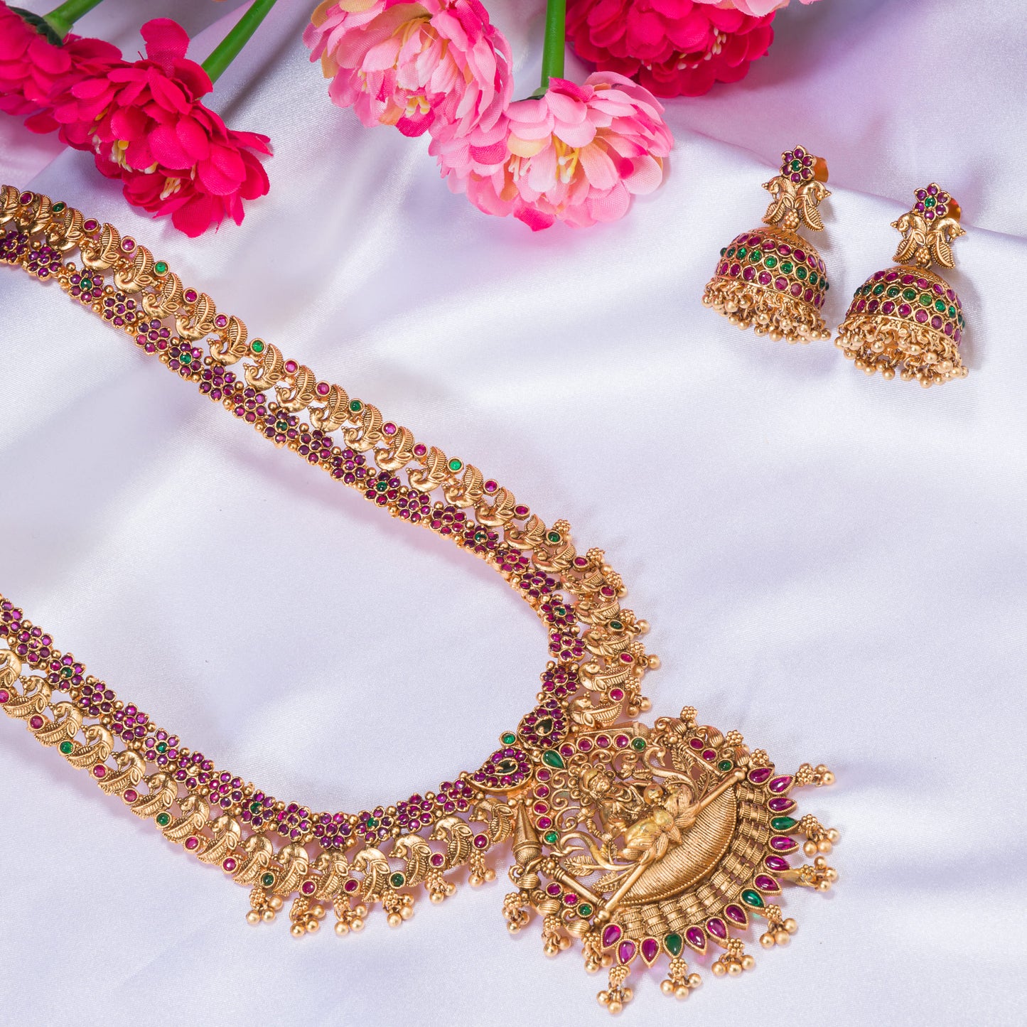 A TEMPLE JEWELLERY WITH RED AND GREEN STONES SHOWCASES TRADITIONAL OPULENCE.