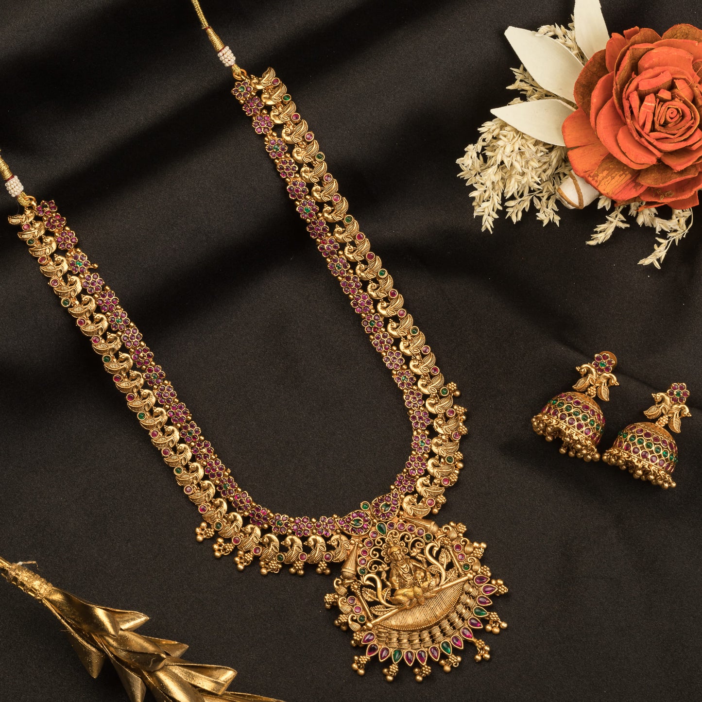 A TEMPLE JEWELLERY WITH RED AND GREEN STONES SHOWCASES TRADITIONAL OPULENCE.