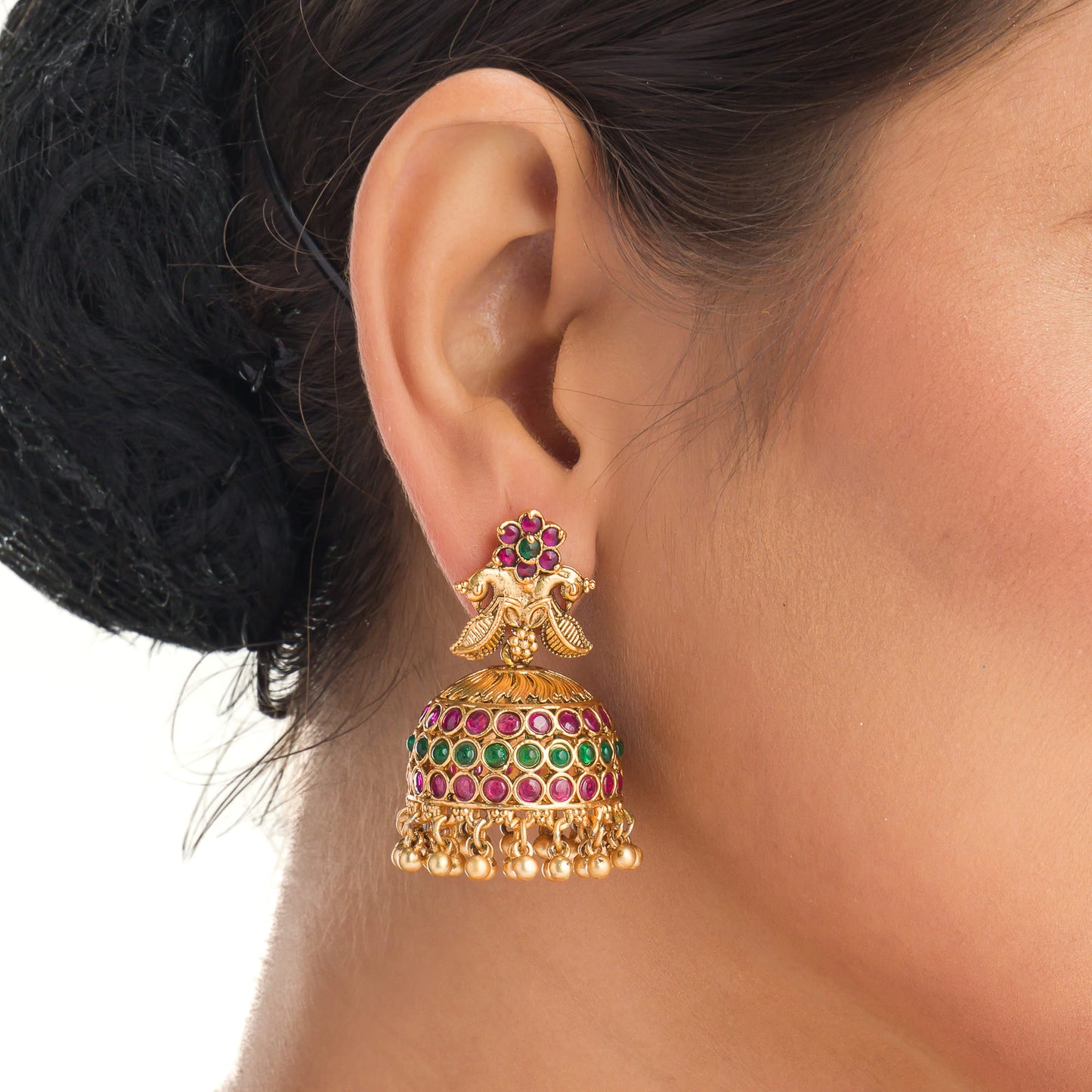 A TEMPLE JEWELLERY WITH RED AND GREEN STONES SHOWCASES TRADITIONAL OPULENCE.