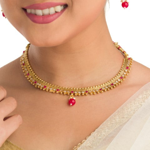 A GOLDEN CHOKER WITH EARRINGS AND MAANG TIKKA CREATES A STUNNING SET.