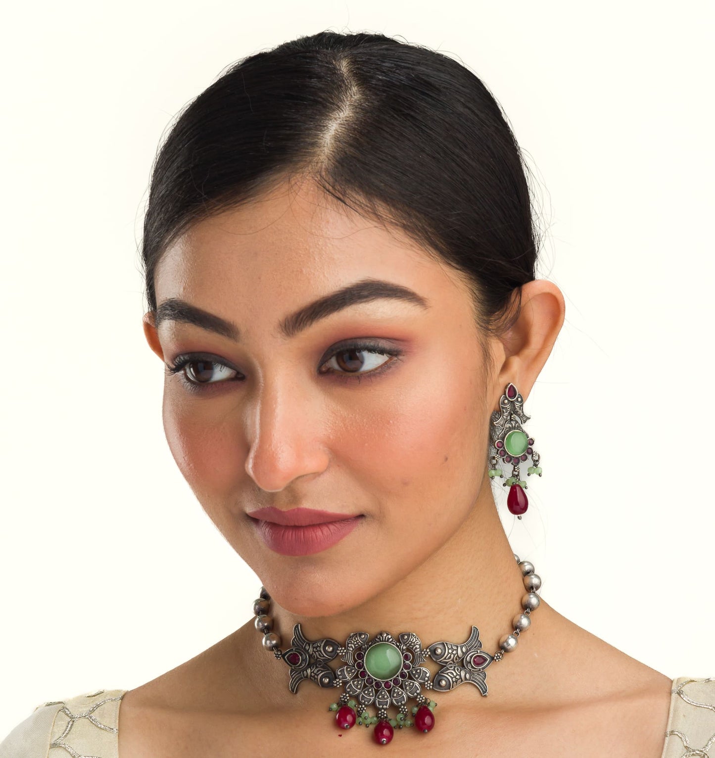 A FISH NECKLACE WITH LIGHT GREEN STONES AND MAROON KUNDAN BLENDS UNIQUE CHARM WITH RICH COLORS.