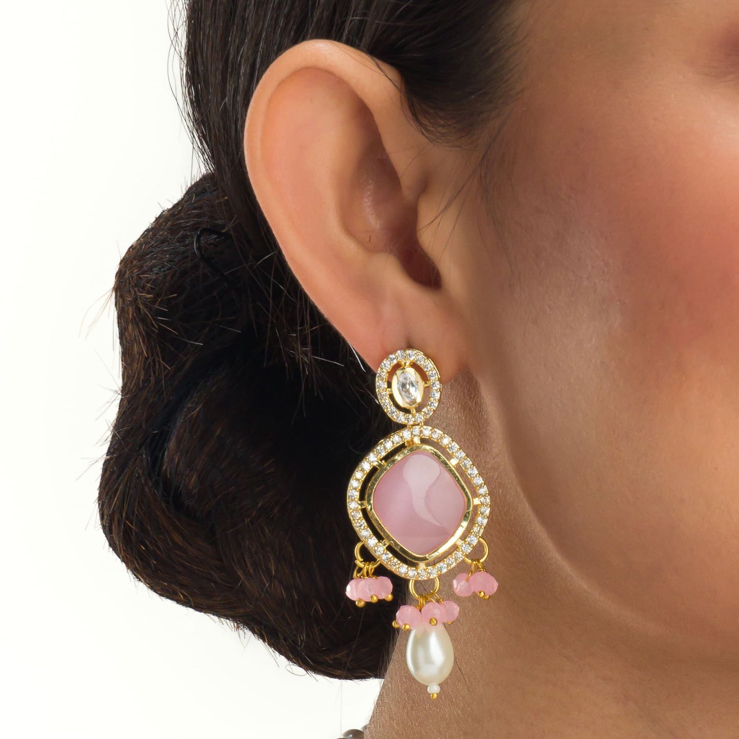 A WHITE PEARL EARRING WITH A PINK STONE IN THE MIDDLE COMBINES CLASSIC ELEGANCE WITH A TOUCH OF VIBRANT, ROMANTIC COLOR.