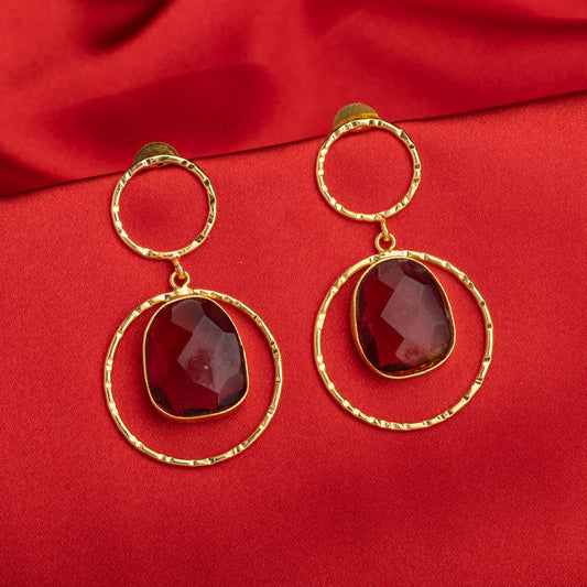 GOLD-TONE EARRINGS WITH A LARGE RED STONE MAKE A BOLD STATEMENT, COMBINING STRIKING COLOR WITH LUXURIOUS SHINE.