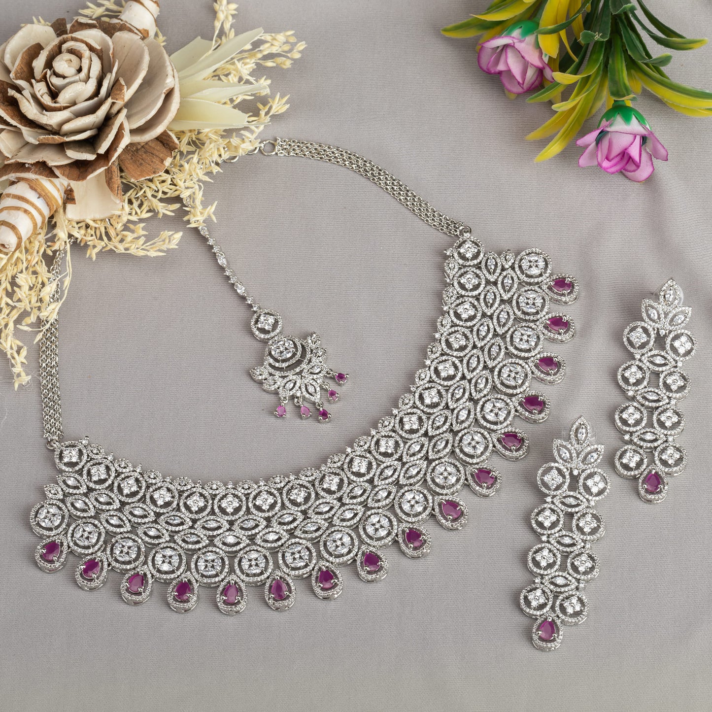 THIS STUNNING PINK COLOUR STONE-STUDDED ZIRCON BRIDAL SET FEATURES A DAZZLING NECKLACE ADORNED WITH INTRICATELY DESIGNED STONES