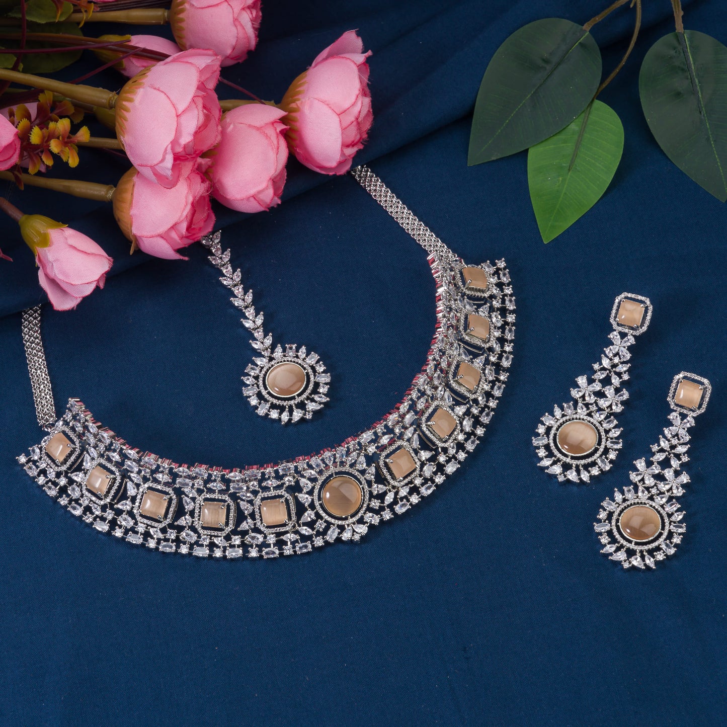 THIS STUNNING SALMON COLOUR STONE-STUDDED ZIRCON BRIDAL SET FEATURES A DAZZLING NECKLACE ADORNED WITH INTRICATELY DESIGNED STONES, PERFECT FOR A REGAL BRIDAL LOOK.