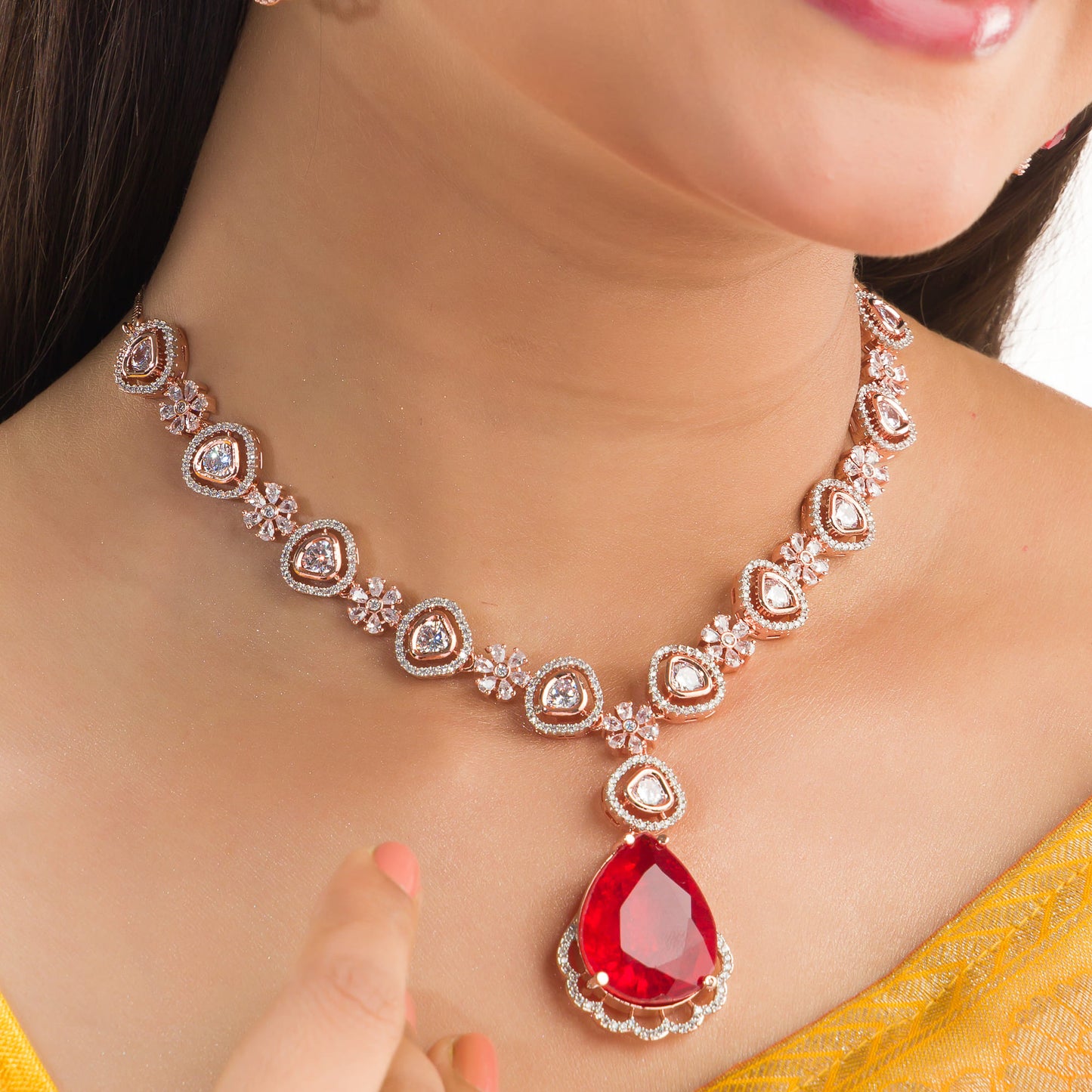 THIS ROSE GOLD POLISHED NECKLACE SET SHOWCASES A STRIKING PENDANT WITH LARGE RED STONES, BEAUTIFULLY ACCENTED BY ZIRCON STUDS.