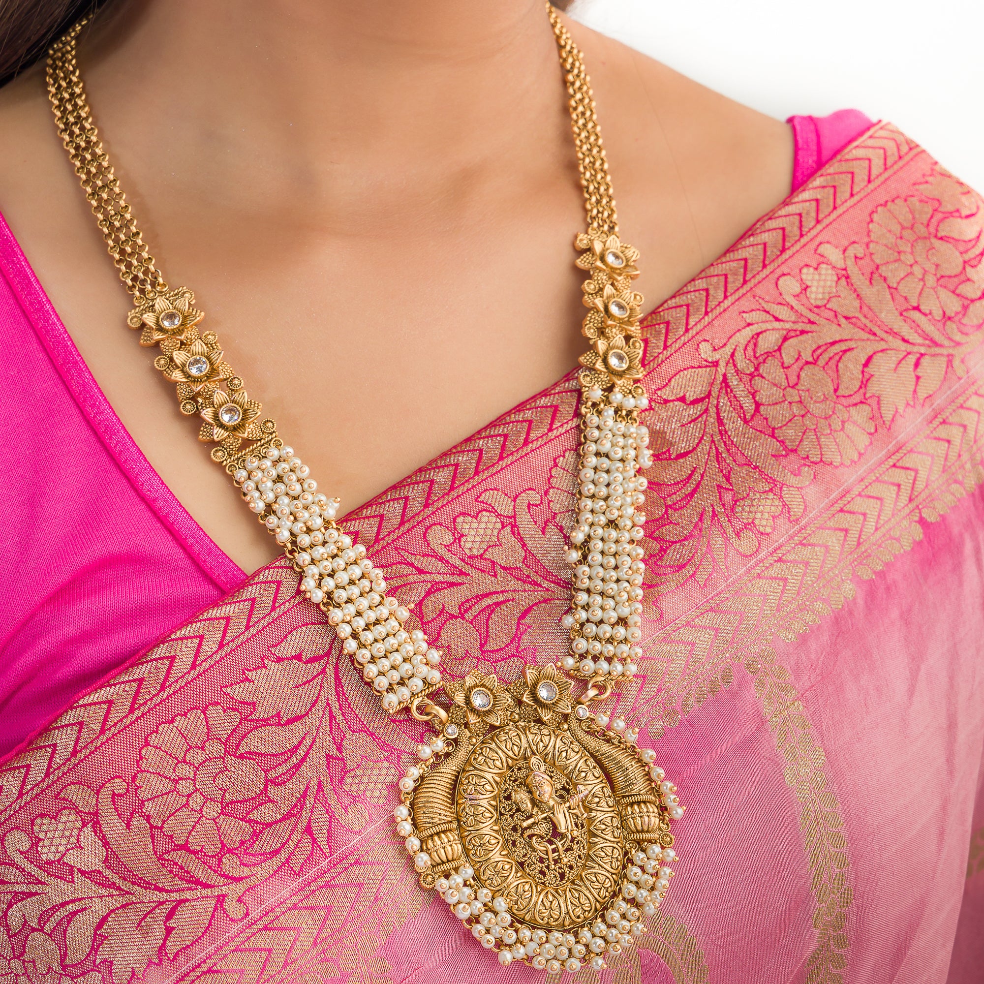 Golden Radha Krishna long necklace set with pearls and matching jhumkas for a divine festive look.
