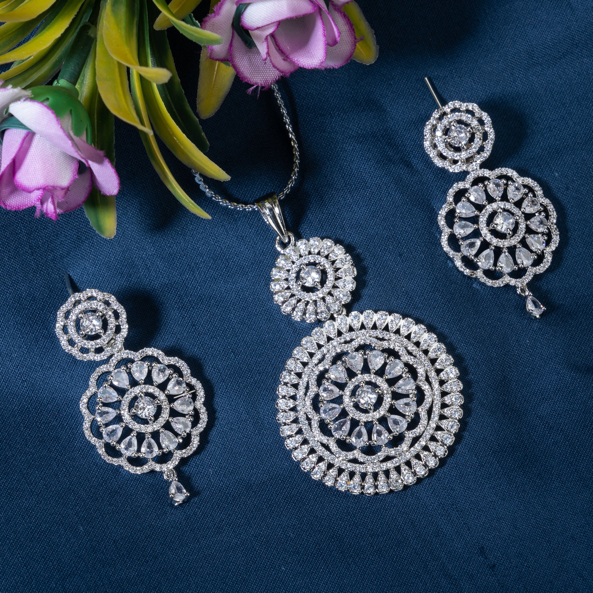 Floral design silver pendant set with white zircon stones and matching earrings for elegance.
