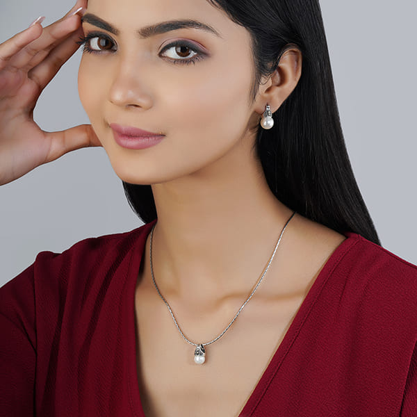 ADORN YOURSELF WITH ELEGANCE WITH THIS PEARL-STUDDED 925 SILVER PENDANT AND EARRINGS SET.