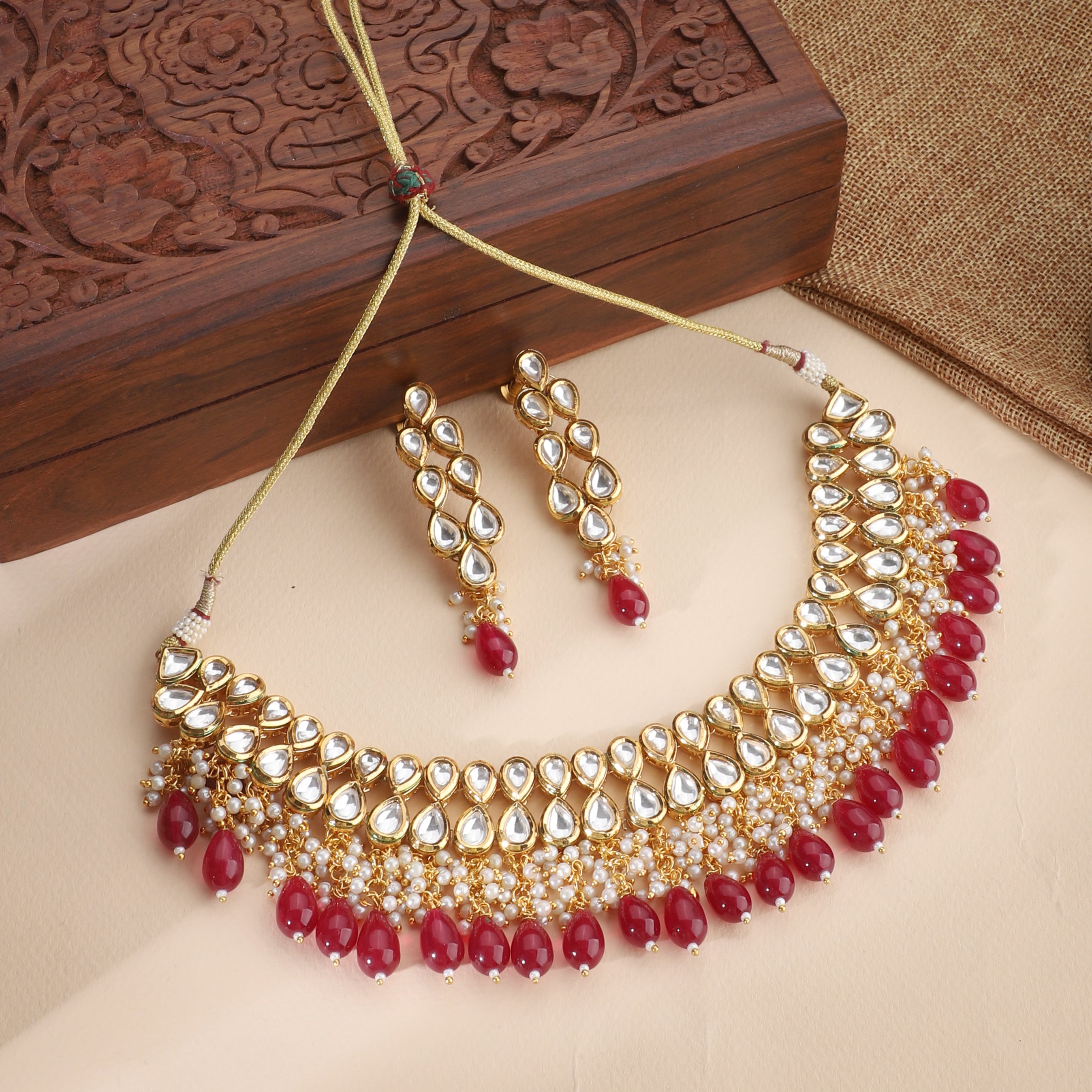 Kundan necklace set with red pearls, featuring two layers of intricate Kundan work and matching earrings.
