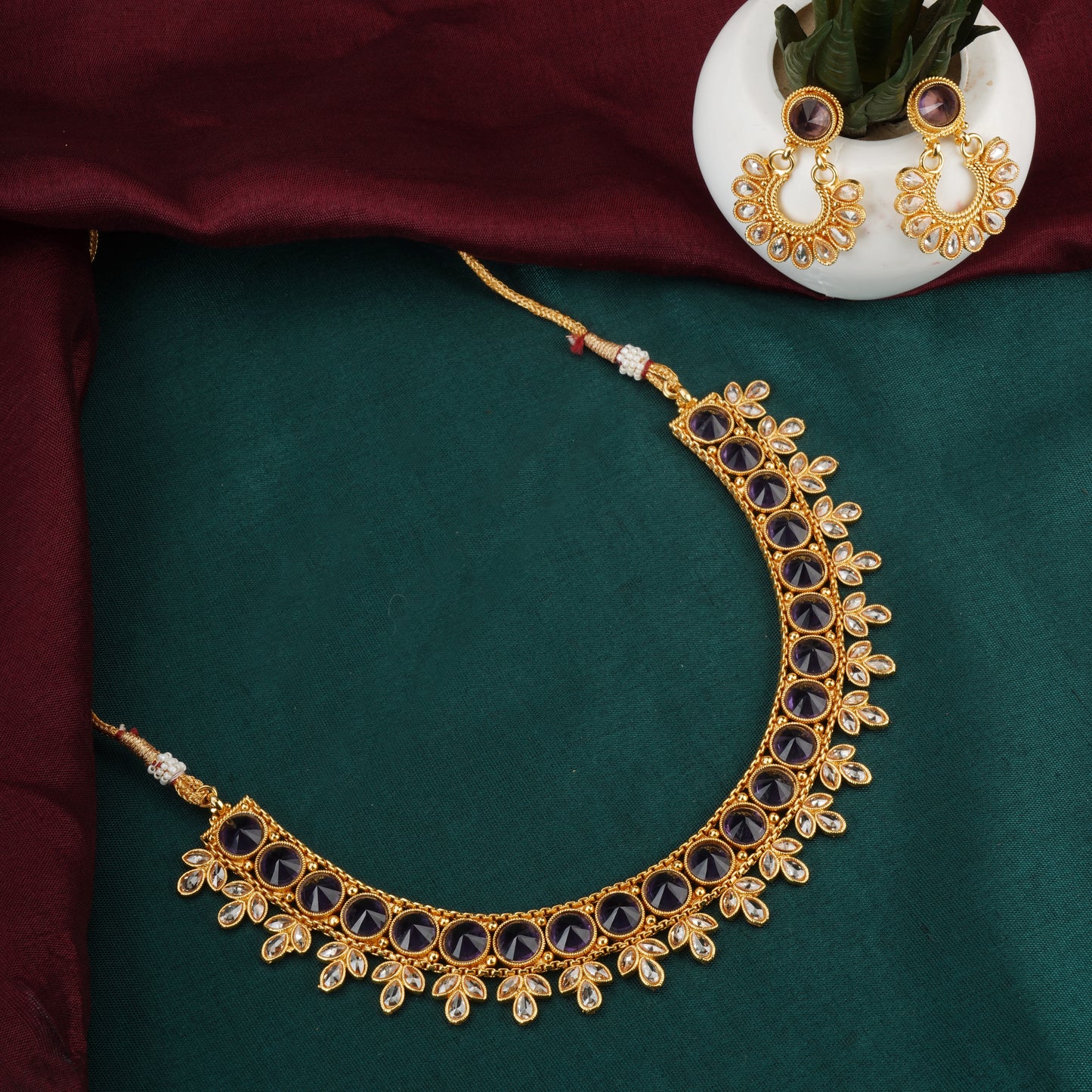 A PURPLE-COLORED KUNDAN-STUDDED NECKLACE SET FEATURES RICH PURPLE STONES PAIRED WITH INTRICATE KUNDAN WORK.