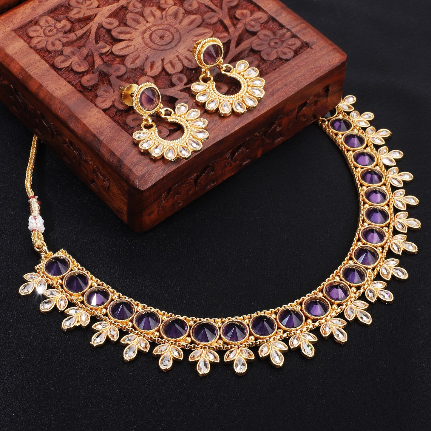 A PURPLE-COLORED KUNDAN-STUDDED NECKLACE SET FEATURES RICH PURPLE STONES PAIRED WITH INTRICATE KUNDAN WORK.