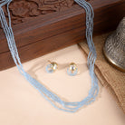 Delicate gold-tone necklace with small blue pearls, offering a subtle and elegant festive charm.
