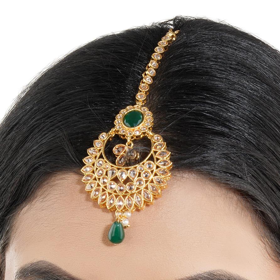 KUNDAN-STUDDED MAANG TIKA FEATURES INTRICATE WORK WITH A SINGLE GREEN PEARL AND A MATCHING STONE.