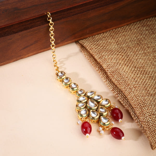 KUNDAN-STUDDED MAANG TIKA WITH RED PEARLS FEATURES INTRICATE WORK