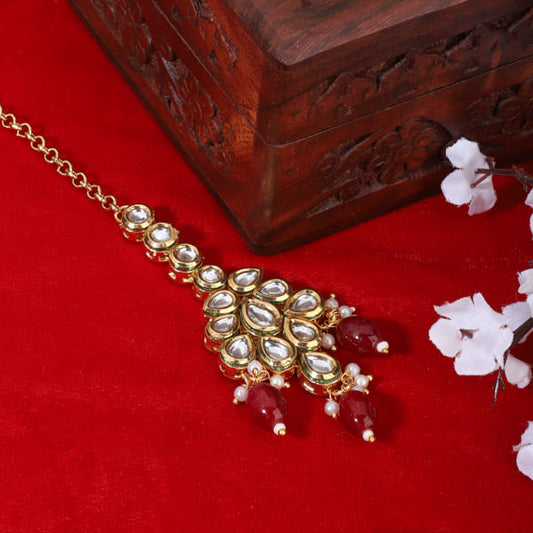 KUNDAN-STUDDED MAANG TIKA WITH RED PEARLS FEATURES INTRICATE WORK