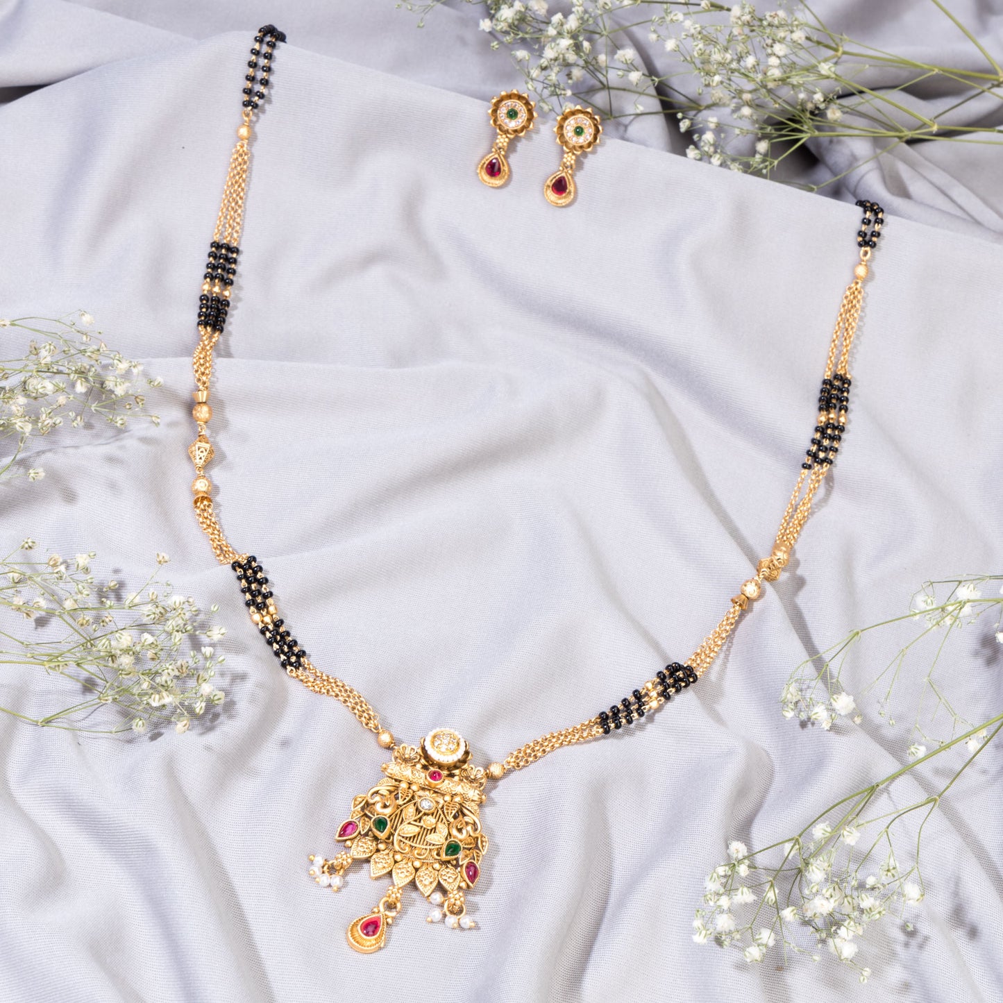 GOLD-TONE LONG MANGALSUTRA SET WITH BLACK BEADS AND MULTICOLORED STONES, COMBINING TRADITIONAL AND VIBRANT ELEMENTS