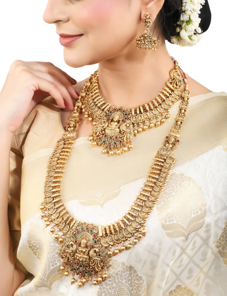 "Goldtone Laxmi Maa crafted long necklace set with matching earrings and Maang Tikka for festive elegance."
