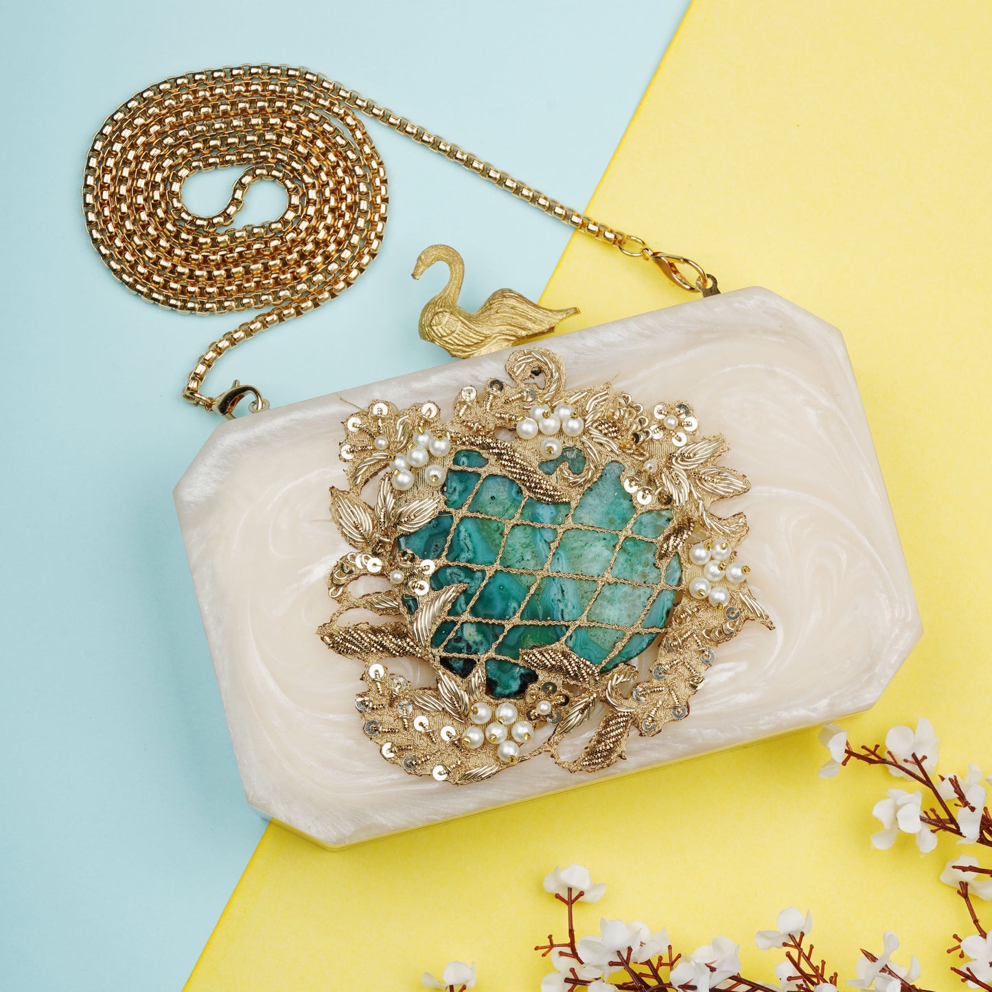 THIS RESIN-EMBELLISHED CLUTCH FEATURES A CAPTIVATING GREEN AGATE STONE AT ITS CENTER. PAIRED WITH A STYLISH SLING CHAIN AND PEACOCK DESIGN KNOB